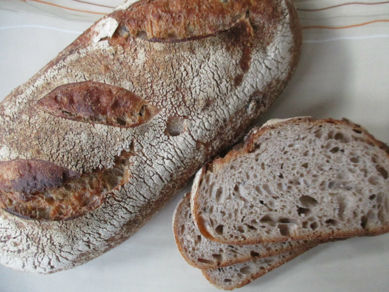 Black_Bean_Sourdough An oval loaf of Black Bean Sourdough with three slices next to it