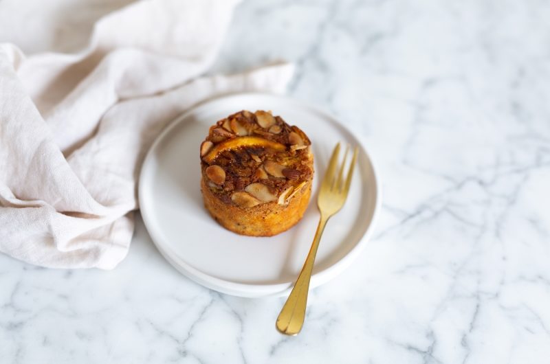 Orange Coconut Cake A round Orange Coconut Cake with almonds on top on a plate