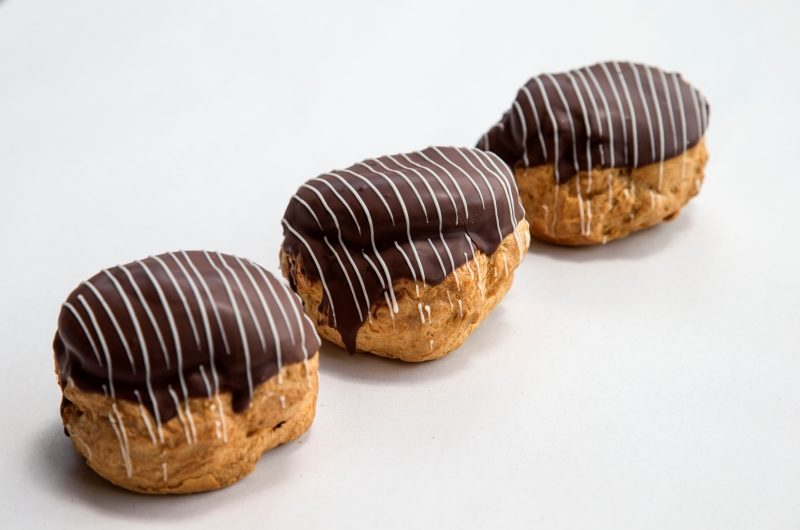 3 round profiterole puff choux pastries covered with melted chocolate