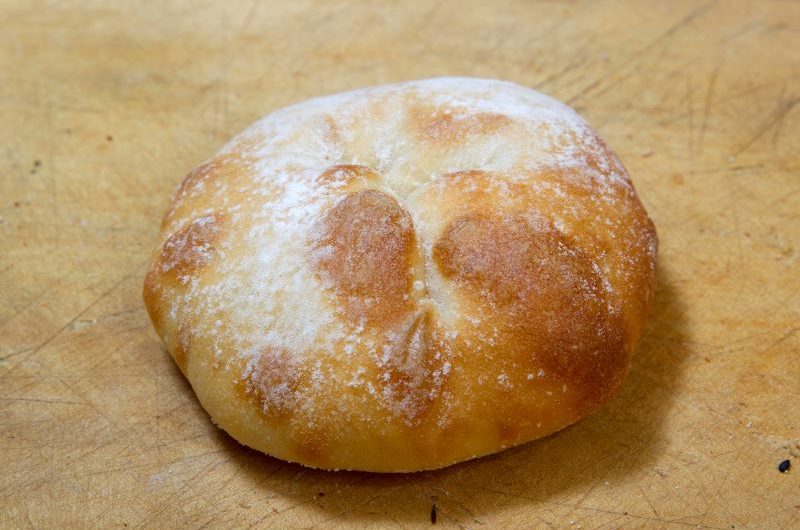Soft bap A floured Turkish bread bap on a wooden chopping board